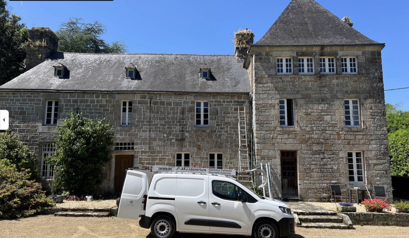 Longère bretonne en pierre avec utilitaire ARJ.COUVERTURE stationné — chantier de restauration de toiture